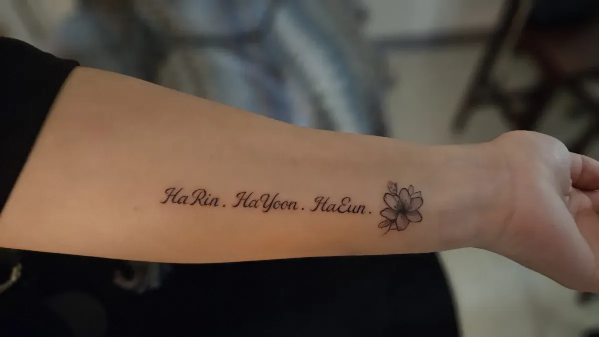 레터링과 작은 플라워가 조화를 이룬 팔 안쪽 타투